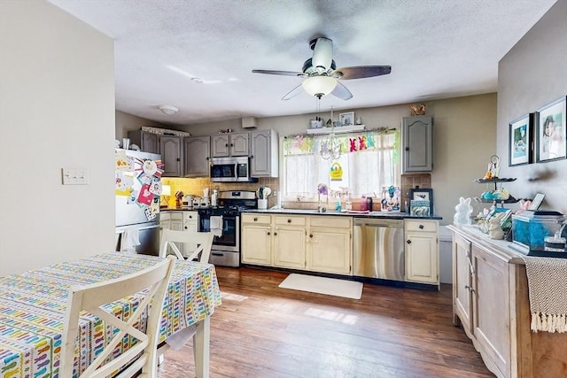 kitchen with dark wood-style floors, a ceiling fan, stainless steel appliances, and decorative backsplash