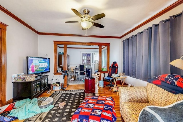 living room with ornamental molding, a ceiling fan, and wood finished floors