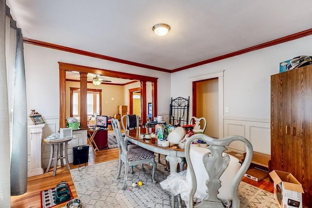 dining area featuring ornamental molding, light wood-style flooring, and decorative columns