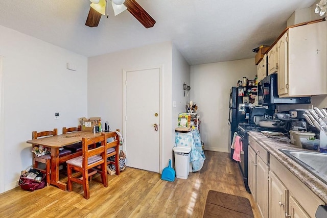 kitchen featuring ceiling fan, light wood-type flooring, black microwave, light countertops, and gas range oven