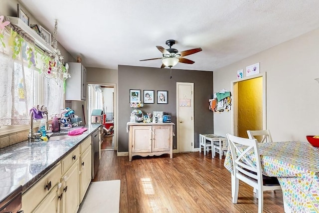 kitchen featuring light wood-style flooring, ceiling fan, baseboards, cream cabinetry, and dishwasher