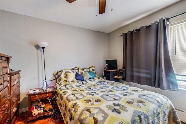 bedroom with ceiling fan, multiple windows, and a baseboard heating unit