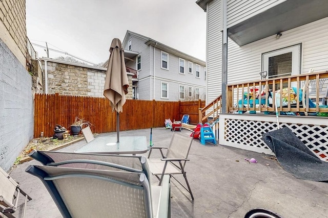 view of patio featuring outdoor dining space, a wooden deck, and a fenced backyard