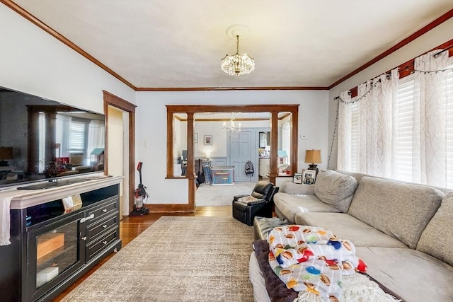 living room with ornamental molding, an inviting chandelier, wood finished floors, and plenty of natural light