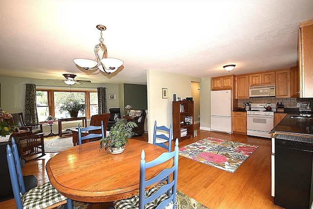 dining room with wood finished floors, a ceiling fan, and a chandelier