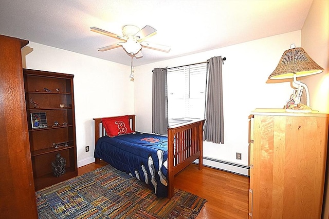 bedroom with baseboard heating, wood finished floors, baseboards, and ceiling fan
