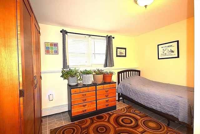 bedroom with baseboard heating, dark tile patterned floors, and baseboards