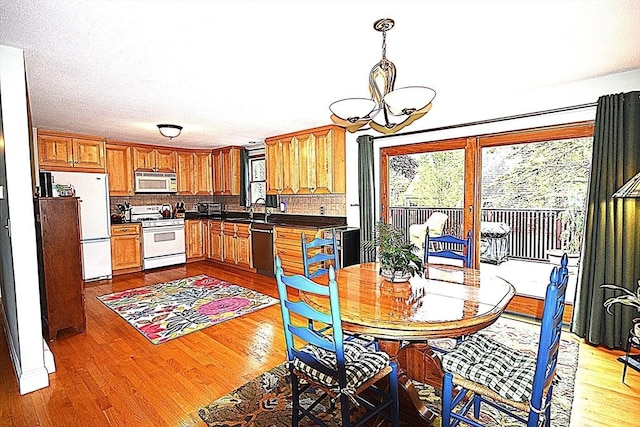dining space with healthy amount of natural light, a chandelier, and light wood-style floors