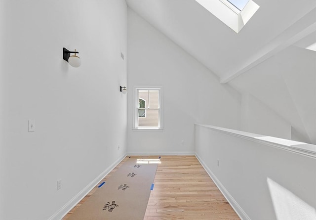 additional living space with a skylight, high vaulted ceiling, and light wood-type flooring