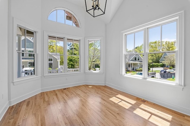 unfurnished sunroom featuring plenty of natural light, a chandelier, and vaulted ceiling