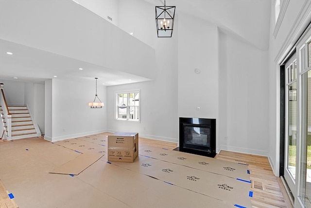 unfurnished living room featuring a high ceiling and a chandelier