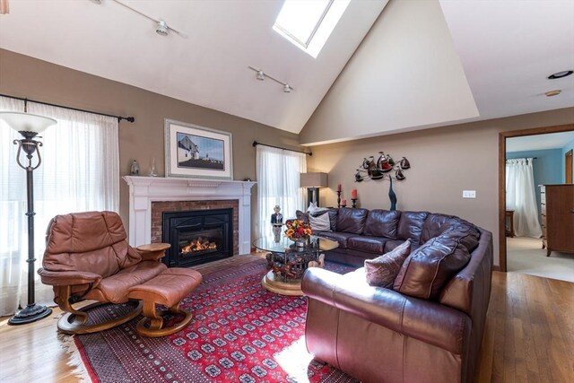 11 Polaris Dr, Mashpee, MA 02649 - living area featuring wood-type flooring, track lighting, a fireplace, high vaulted ceiling, and a skylight