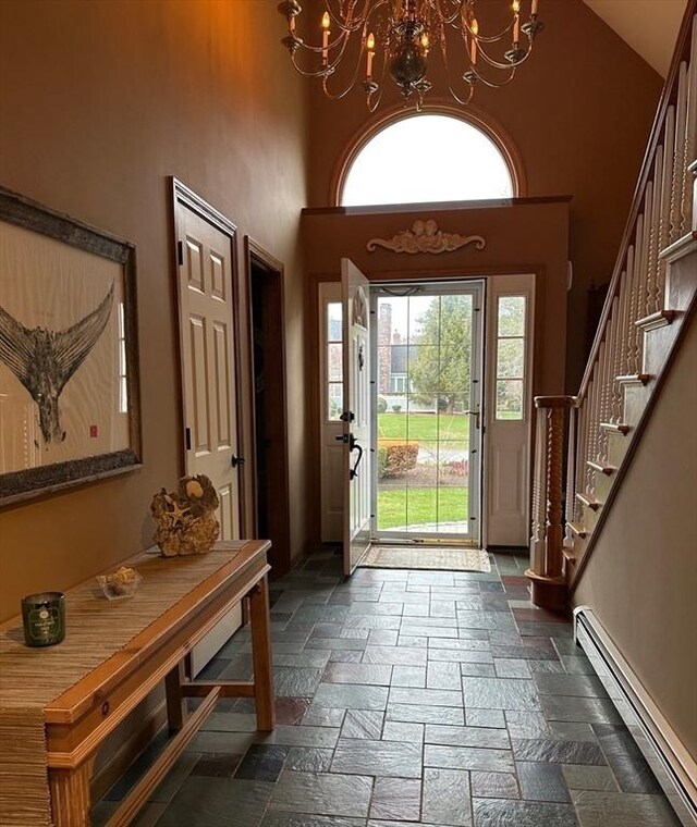 11 Polaris Dr, Mashpee, MA 02649 - entryway featuring stone tile floors, a baseboard heating unit, an inviting chandelier, a towering ceiling, and stairs