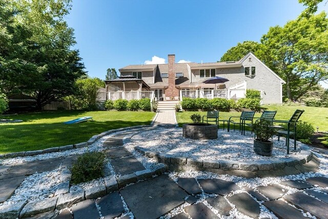 11 Polaris Dr, Mashpee, MA 02649 - back of house with a wooden deck, a yard, a chimney, and an outdoor fire pit
