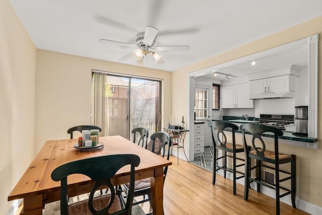 dining area with a ceiling fan, light wood-style flooring, and baseboards