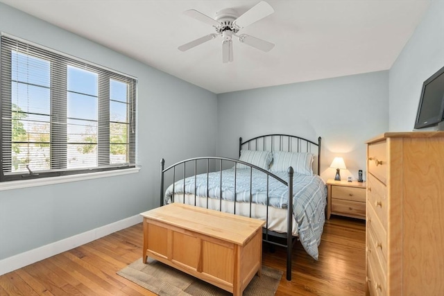 bedroom featuring baseboards, light wood finished floors, and a ceiling fan