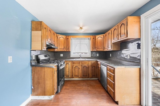 kitchen with under cabinet range hood, stainless steel appliances, a sink, and brown cabinetry