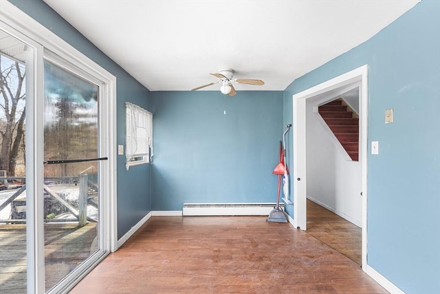 unfurnished room with baseboards, ceiling fan, stairway, wood finished floors, and a baseboard heating unit