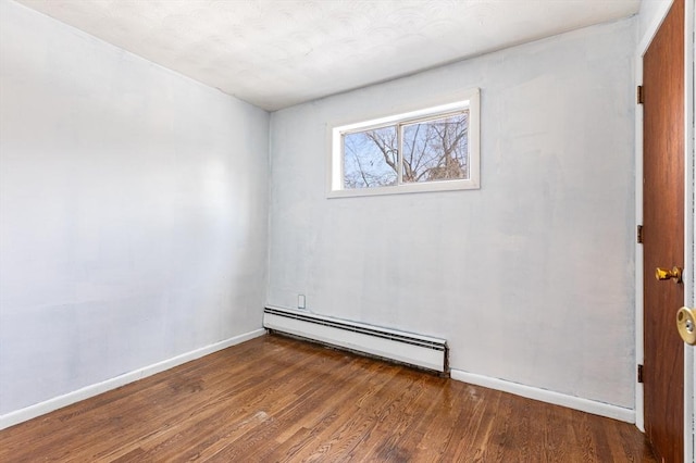 spare room with a baseboard radiator, baseboards, and wood finished floors