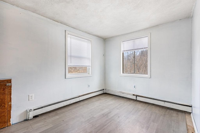 spare room featuring a baseboard radiator, a textured ceiling, and wood finished floors