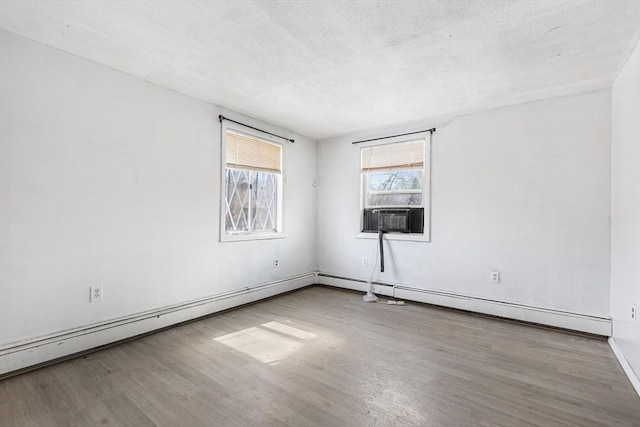 unfurnished room with a baseboard heating unit, a textured ceiling, cooling unit, and wood finished floors