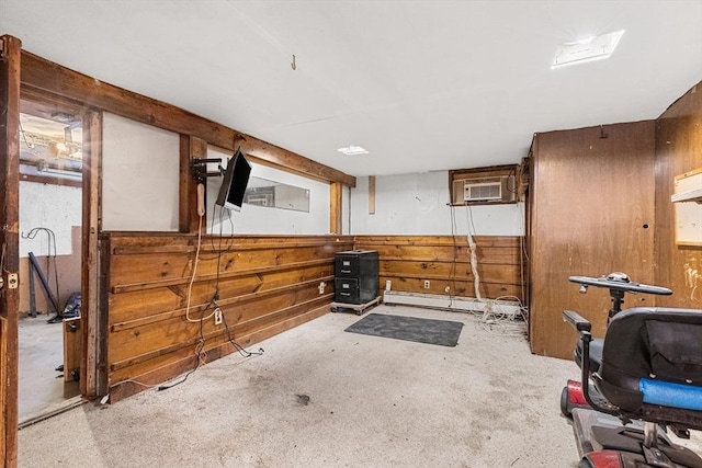 exercise room with a baseboard heating unit, an AC wall unit, wainscoting, and wooden walls