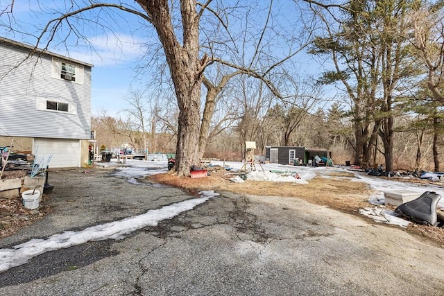 view of yard with a garage, a storage shed, aphalt driveway, and an outdoor structure