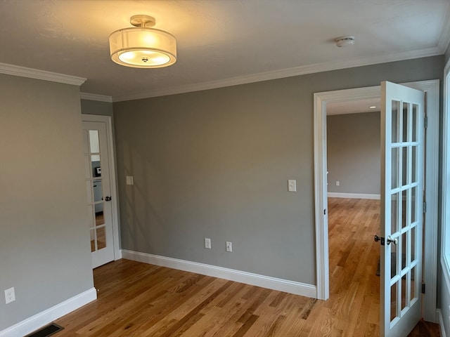 spare room featuring light wood-type flooring, visible vents, and baseboards