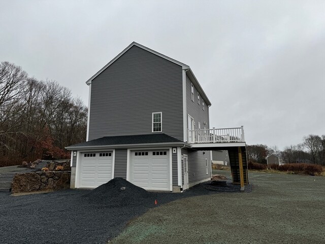 view of property exterior featuring a garage, driveway, stairway, and a wooden deck