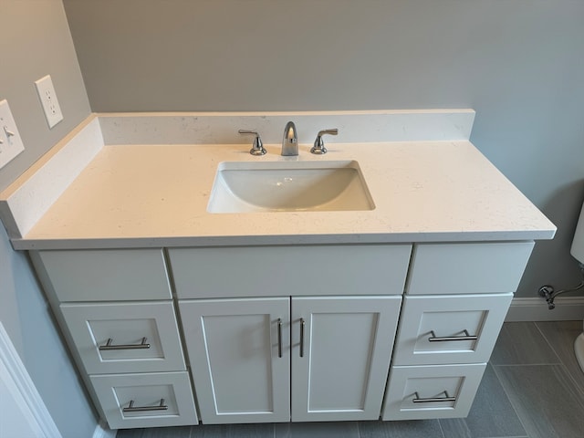 bathroom with toilet, vanity, and baseboards