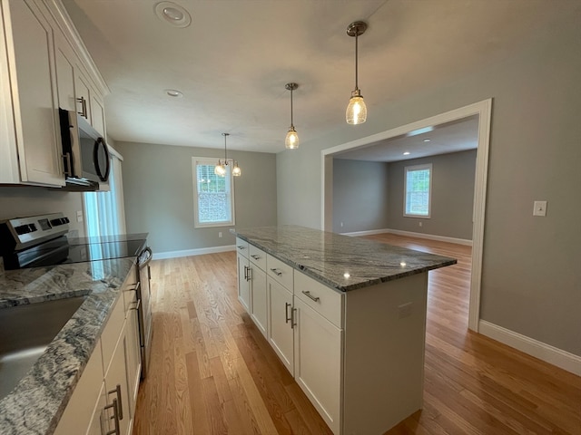 kitchen featuring stainless steel appliances, a wealth of natural light, a kitchen island, and light wood-style flooring