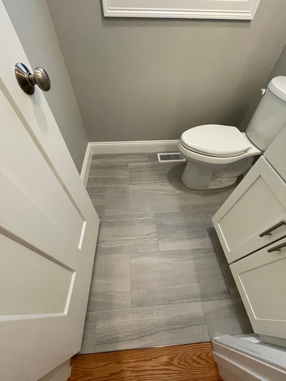 bathroom with toilet, visible vents, and baseboards