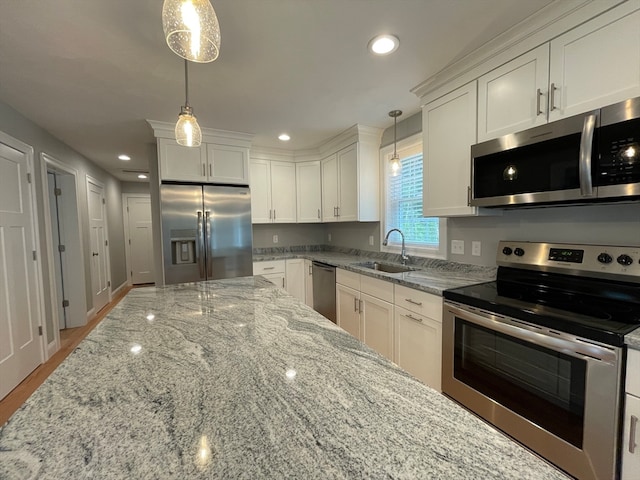 kitchen featuring light stone countertops, stainless steel appliances, sink, pendant lighting, and white cabinets