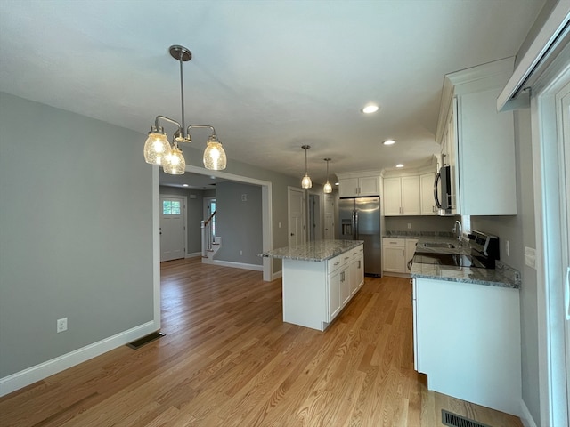 kitchen with light wood-style flooring, a kitchen island, white cabinetry, visible vents, and stainless steel fridge with ice dispenser