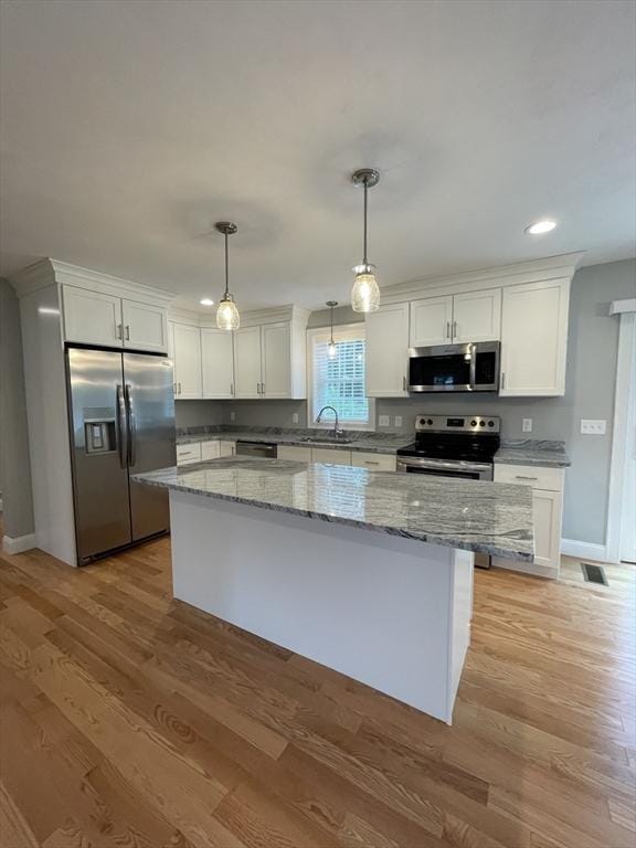 200 Pine St, Rehoboth, MA 02769 - kitchen with stainless steel appliances, a kitchen island, white cabinetry, light wood-style flooring, and light stone counters