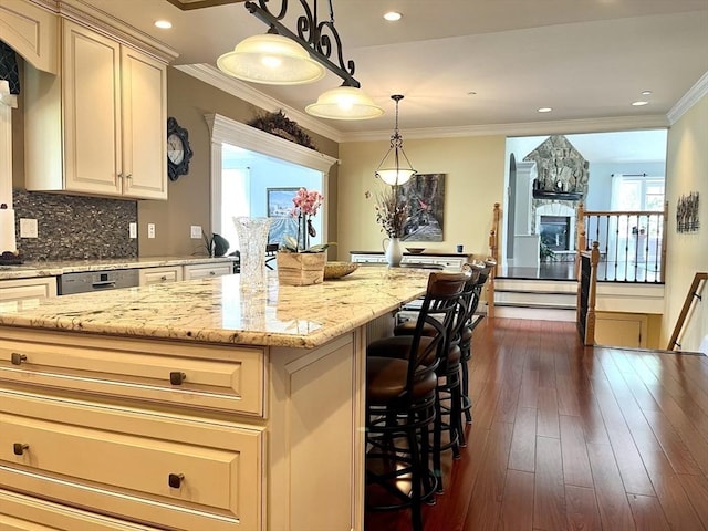 kitchen with a stone fireplace, a kitchen breakfast bar, ornamental molding, backsplash, and dark wood-style floors