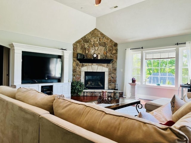 living room with vaulted ceiling, ceiling fan, a fireplace, and visible vents