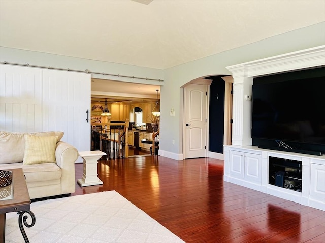 living area with arched walkways, dark wood-style flooring, and baseboards