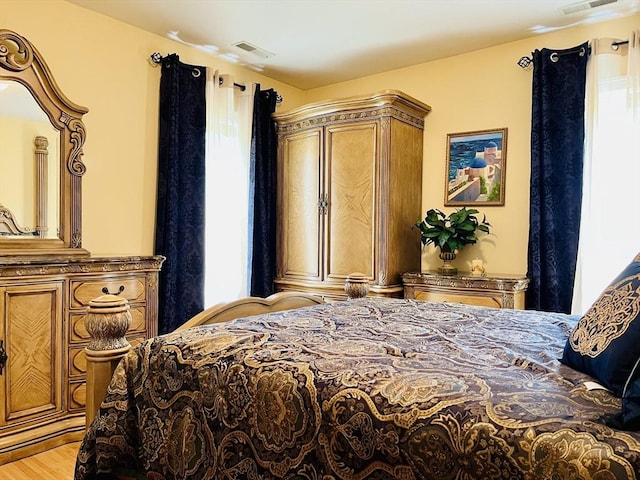 bedroom with light wood-style floors and visible vents