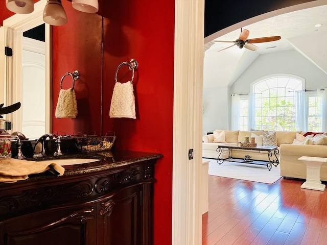 bathroom featuring ceiling fan, wood finished floors, vanity, and lofted ceiling