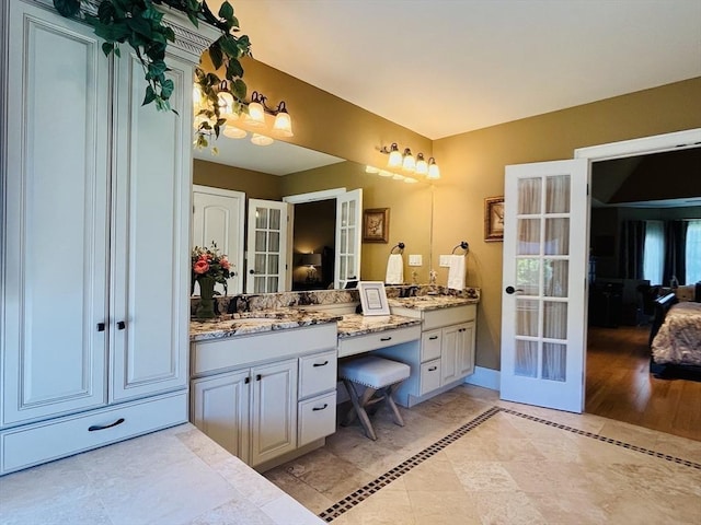 bathroom featuring double vanity, ensuite bath, a sink, and french doors