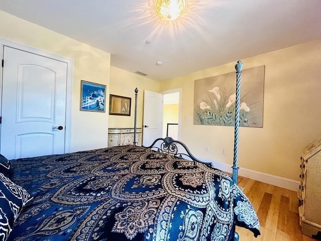 bedroom with visible vents, baseboards, and wood finished floors