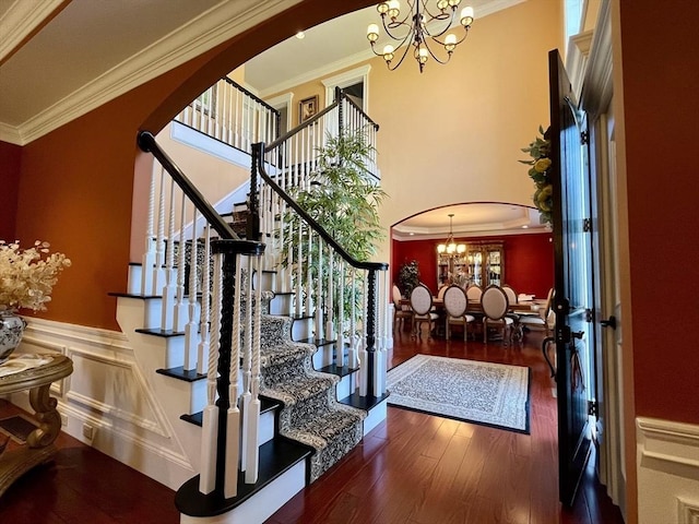 foyer with arched walkways, ornamental molding, and an inviting chandelier