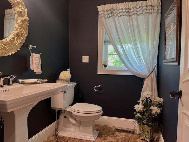 bathroom featuring toilet, visible vents, baseboards, and a sink