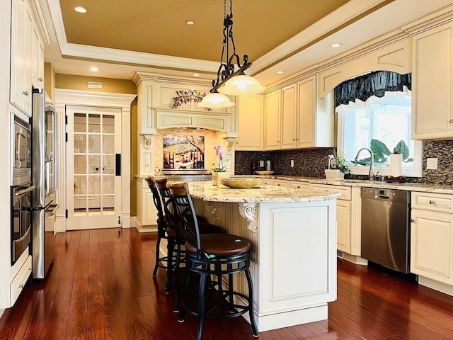 kitchen with stainless steel appliances, a center island, a raised ceiling, and dark wood-style floors