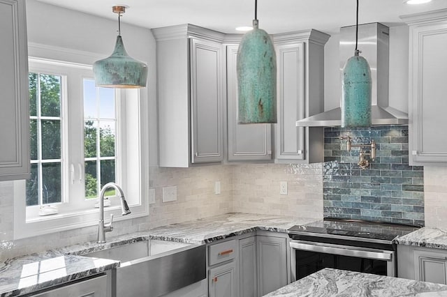 kitchen featuring a wealth of natural light, wall chimney exhaust hood, pendant lighting, and stainless steel range with electric stovetop