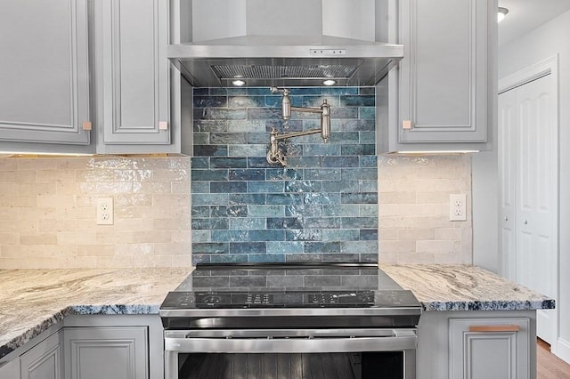 kitchen with electric range, gray cabinets, wall chimney range hood, and tasteful backsplash