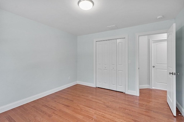 unfurnished bedroom with light wood-type flooring and a closet