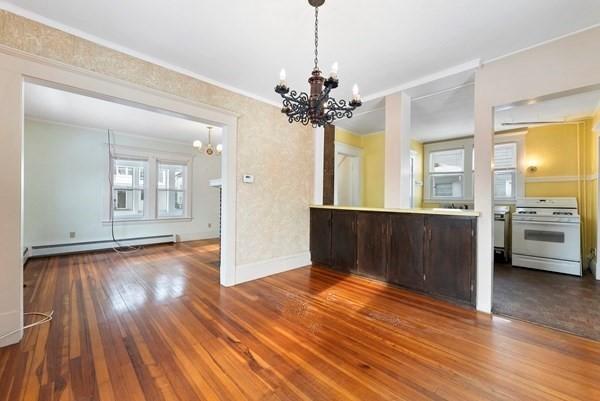 interior space featuring a baseboard heating unit, stove, a notable chandelier, and wood finished floors