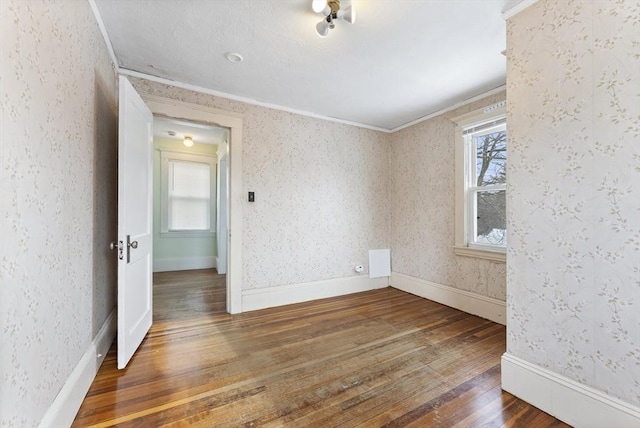 unfurnished room with wallpapered walls, baseboards, dark wood-style floors, and ornamental molding